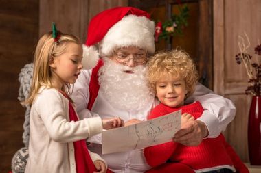 2 børn der viser en tegning til en mand i julemandskostume