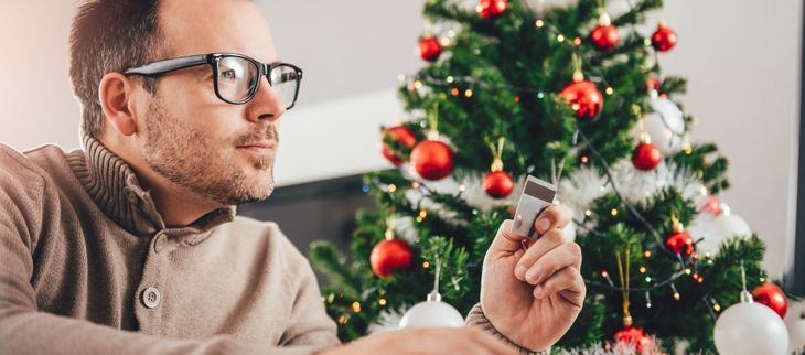 Mand med kreditkort foran juletræet