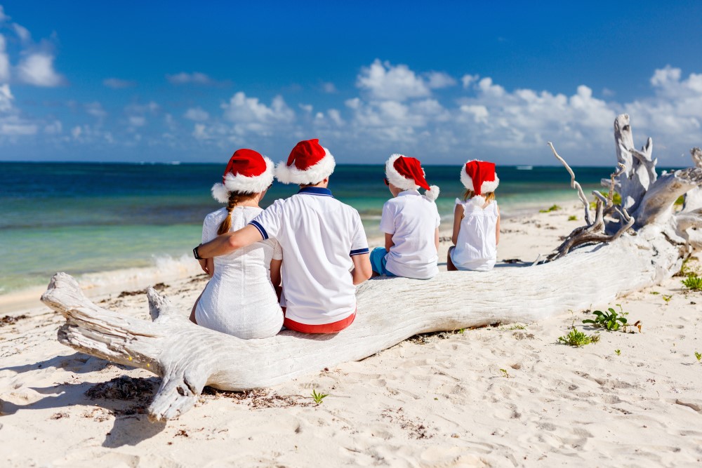 Familie med nissehuer på ved varm strand