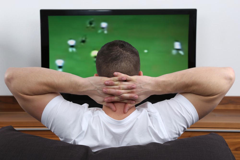 Mand der ser fodbold på TV